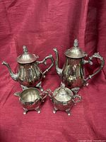 All four silver-plated pieces together on red cloth background