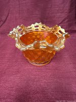 Side view showing marigold carnival glass bowl, basketweave pattern and ruffled lattice rim