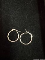 Both sterling silver hoop earrings closed view on black background