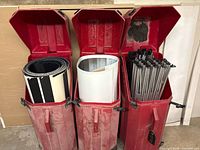 Three red cases open showing rolled panels and frame poles