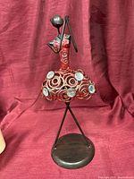 Front view of abstract bronze ballerina statue with red wire skirt and jewel accents
