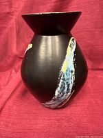 Full side view of black ceramic vase with multicolor glaze