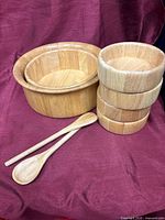 All pieces: large bowl with nested medium bowl, four small bowls stacked, wooden fork and spoon