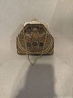 Front view of beaded minaudière showing bead pattern, metal frame and chain strap