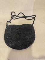 Front view of black beaded shoulder bag showing bead pattern and cord strap