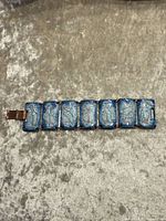 Front view of bracelet showing blue enamel panels with bird motif