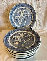 Stack of blue and white dinner plates with one displayed upright