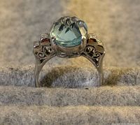 Side profile of ring showing filigree gallery and oval blue topaz