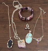 All six jewellery pieces laid out on wood surface