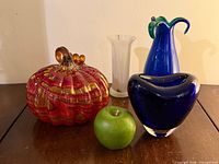 Group shot of pumpkin, blue vase, white vase with apple for scale