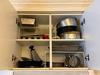 overview of cupboard showing multiple baking pans, tins, grater and accessories