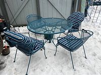 table and four chairs arranged outdoors in snow