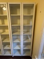 Front full view of white IKEA Billy bookcase with glass doors and shelves