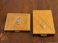 Top view of both compacts showing 10K appliqué with gemstones and diamond pattern lid