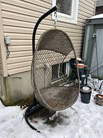 Full front view of resin wicker egg chair on metal stand outdoors in snow