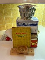 Overall lot stacked: aluminium fluted mold, Delft tin, recipe booklet, red tin, wooden mold visible