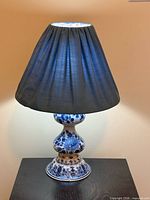 Entire lamp lit with shade showing Delft ceramic base