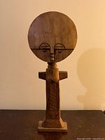 Full view of carved wood fertility doll on base