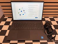 Laptop open on setup screen with power adapter beside