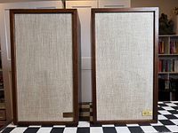 Both AR-2ax speakers with grilles on, showing badges and fabric