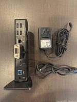 Rear view of docking station showing HDMI, DVI, 4× USB 2.0, Ethernet, power; AC adapter and USB cable beside unit