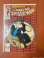 Front cover in bag and board showing 25th Anniversary banner and Venom art