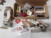 Overview of open carton with numerous plastic-cased needles, cartridges, headshells and a side bundle labeled Turntb needles