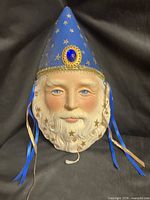 Full view of ceramic wizard mask showing hat, face, ribbons, pull cord