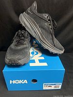 Pair of black Hoka Challenger ATR 7 sneakers on blue Hoka box, side and top views visible