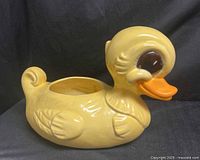 Left side view of yellow ceramic duck planter showing overall shape and opening
