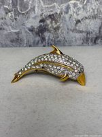 front view showing goldtone dolphin with pavé clear rhinestones and green eyes
