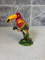 Front view of bejeweled enameled toucan trinket box on branch base