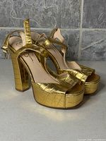 Side view of gold crocodile-embossed platform sandals showing heel and straps