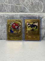 Front of two gold fan art Pokemon cards in sleeves: Magikarp EX and Shining Charizard