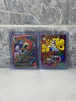 Front view of both holographic fan art cards in sleeves
