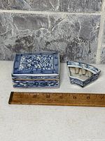 Rectangular lidded box and triangular box beside ruler for scale