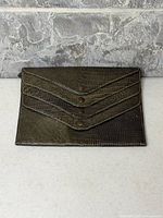 Front view of crocodile skin wallet showing tri-flap design and snap buttons