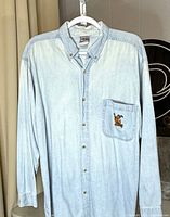 Full front view of light-wash denim Scooby-Doo shirt on hanger