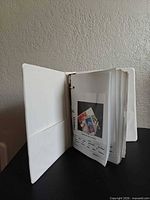 open white binder showing interior pages with stamps