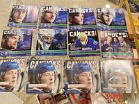 Twelve Vancouver Canucks programs laid out: eight 2011 blue-cover issues, four 2017 Brock Boeser issues