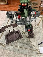 Overview of partially assembled GI Joe Headquarters Command Center with tower, walls, vehicle bay and detached terrain pieces