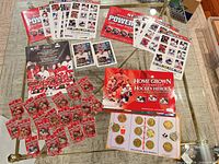 Overview of all memorabilia on glass table: sticker album, sticker sheets, coin folder, coins, player cards, program