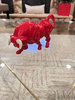 Side view of red ceramic bull figurine showing overall form and glaze