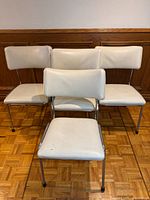 Front view of all four ivory vinyl chairs
