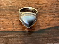 Top view of sterling silver ring with triangular abalone shell on wood surface