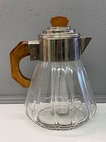 Full view of ribbed glass carafe with chrome collar, wood handle and finial
