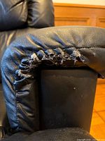 Right armrest showing torn faux leather exposing stuffing