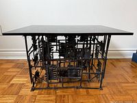 Full view of brutalist metal table with smoked glass top