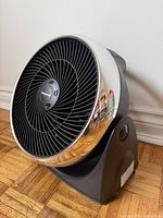 Front three-quarter view of fan showing grill, bezel, stand