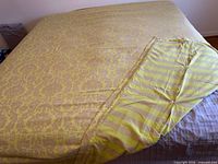 Full view of duvet cover on bed showing damask front and folded striped reverse